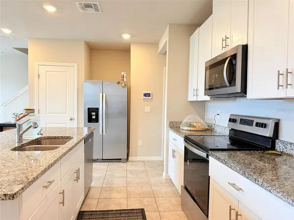 a kitchen with stainless steel appliances granite countertop a stove a sink a refrigerator and a refrigerator