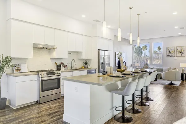 a kitchen with kitchen island a stove a table a sink and cabinets