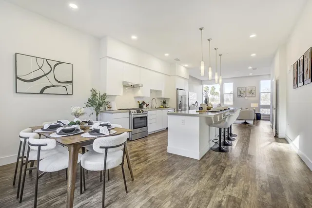 a dining room with stainless steel appliances kitchen island granite countertop a table chairs and a refrigerator