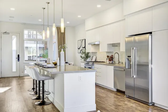 a kitchen with kitchen island a counter top space a sink a refrigerator and a view of living room
