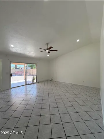 an empty room with windows and ceiling fan
