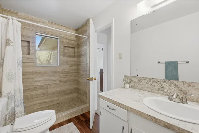 a bathroom with a granite countertop sink toilet and shower