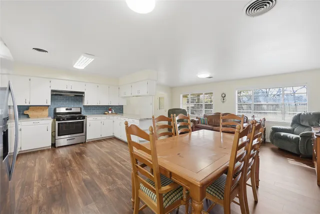 a living room with stainless steel appliances furniture a dining table and kitchen view