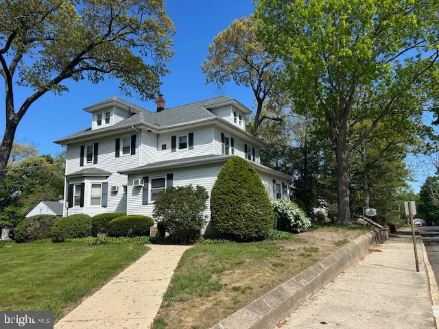 a view of a white house with a big yard and potted plants and large trees