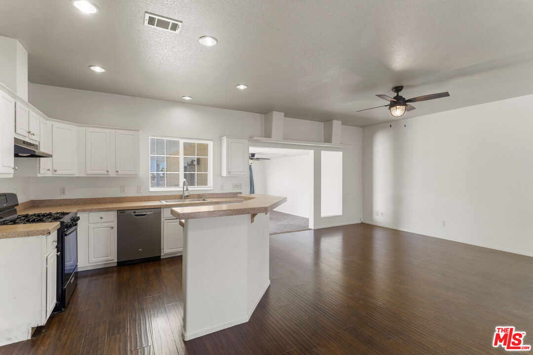 13072 Anderson Ranch Road Phelan, CA 92371 - Photo 3 of 25 an open kitchen with granite countertop a stove top oven sink and wooden floor