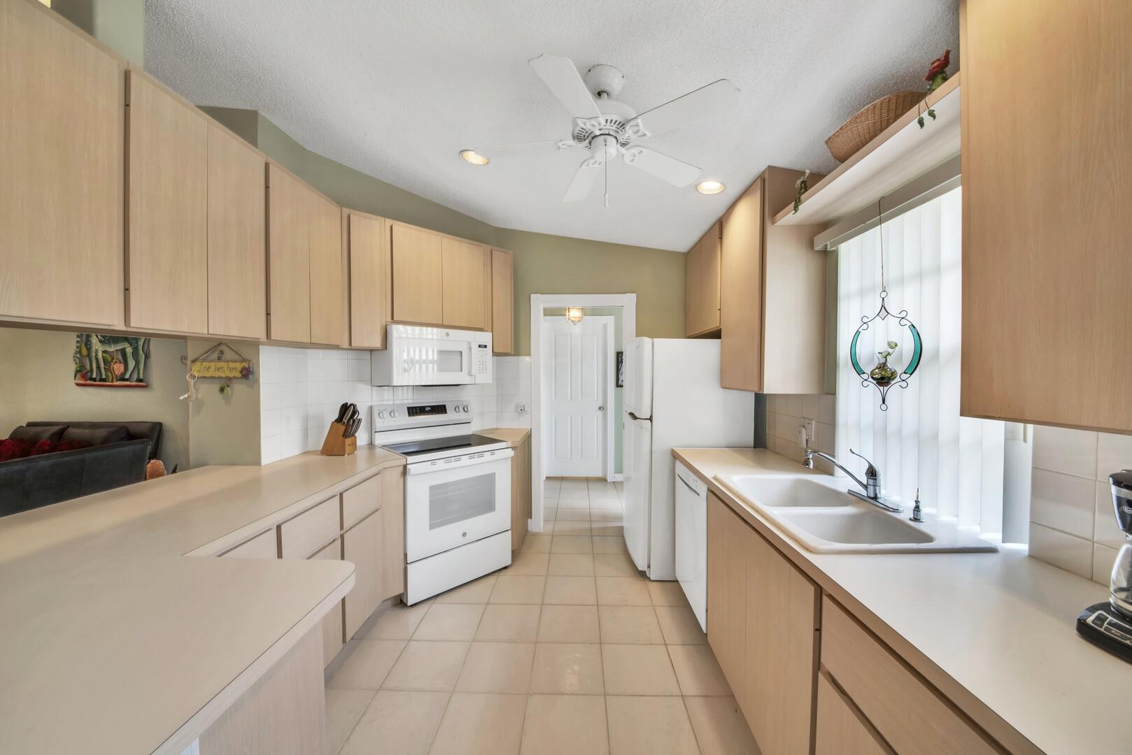4220 Royal Oak Drive Palm Beach Gardens, FL 33410 - Photo 6 of 35 a kitchen with white cabinets and white appliances