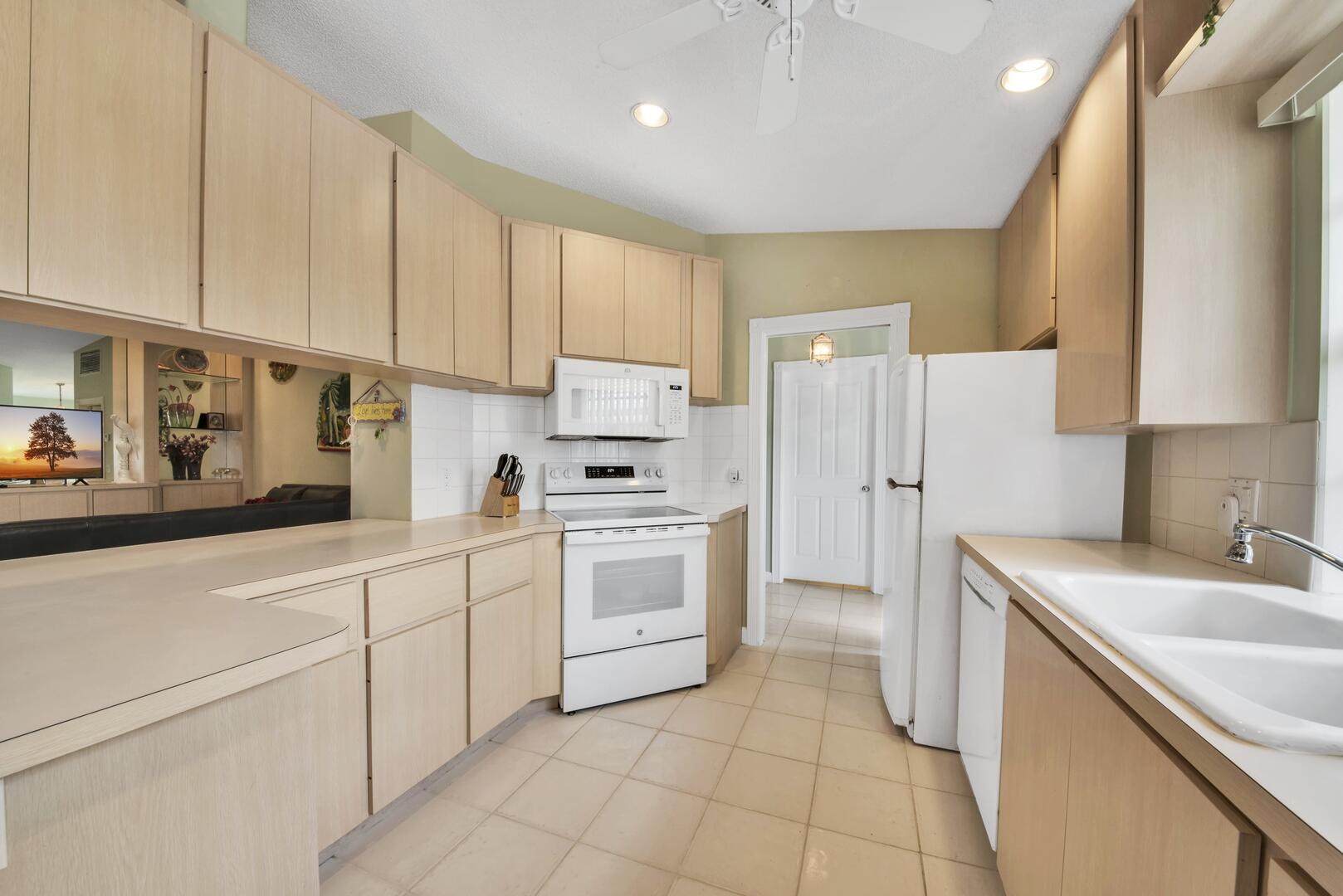 4220 Royal Oak Drive Palm Beach Gardens, FL 33410 - Photo 7 of 35 a kitchen with white cabinets a sink stove and refrigerator