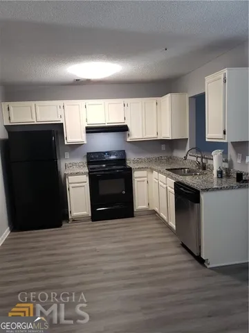 a kitchen with granite countertop a refrigerator stove top oven and cabinets