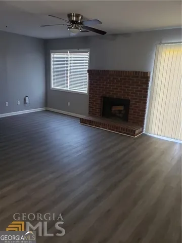 an empty room with wooden floor a fireplace and windows