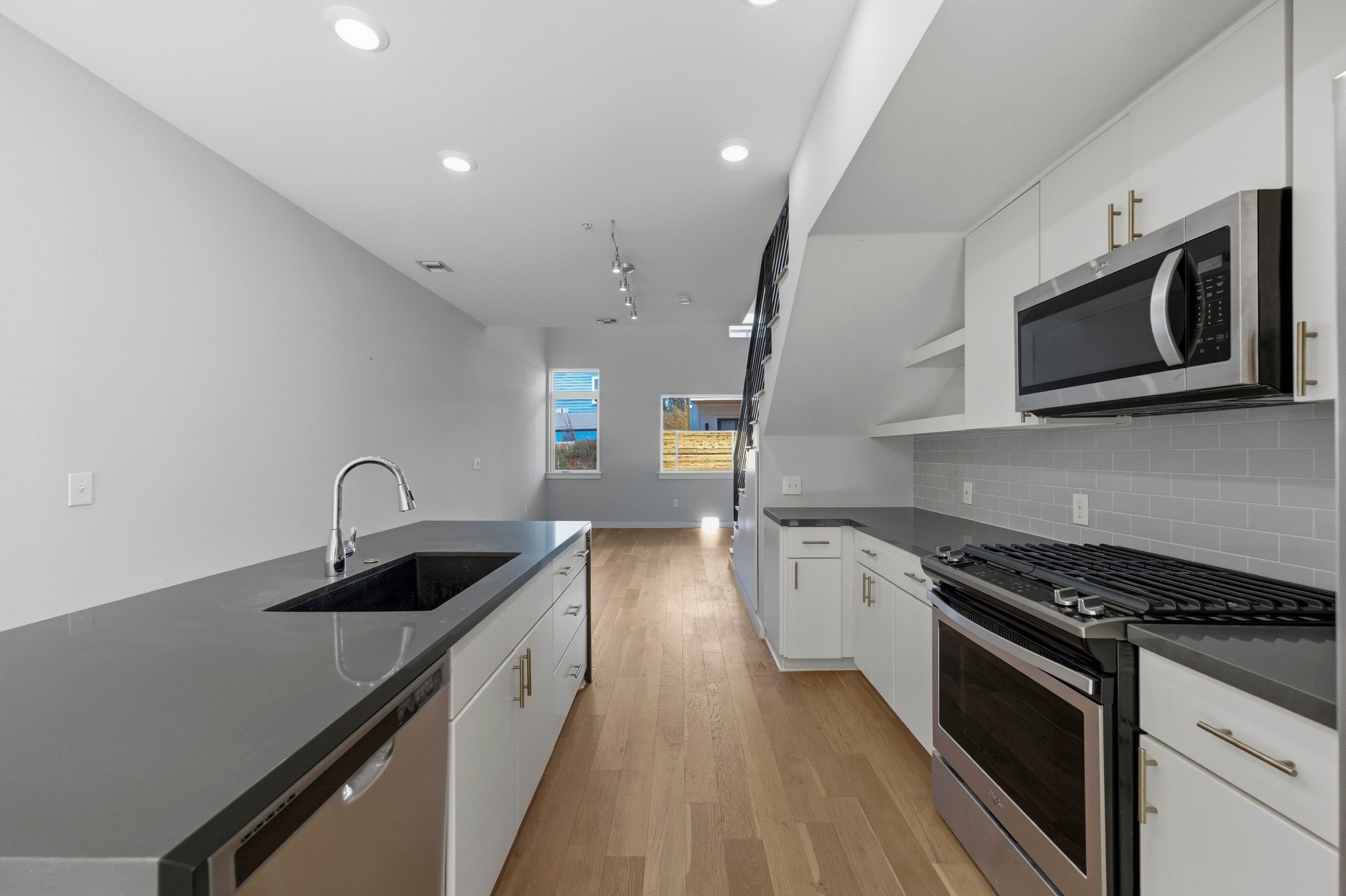 2002 East 7th Street, Unit 242 Austin, TX 78702 - Photo 2 of 34 Kitchen with stainless steel appliances, light wood-style flooring, white cabinets, open shelves, and a kitchen island with sink