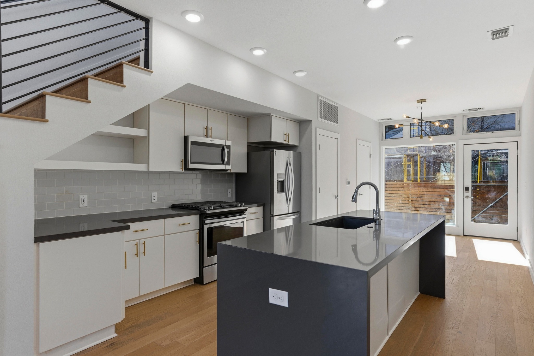 2002 East 7th Street, Unit 242 Austin, TX 78702 - Photo 6 of 34 Kitchen with stainless steel appliances, light wood-style flooring, hanging light fixtures, and a center island with sink