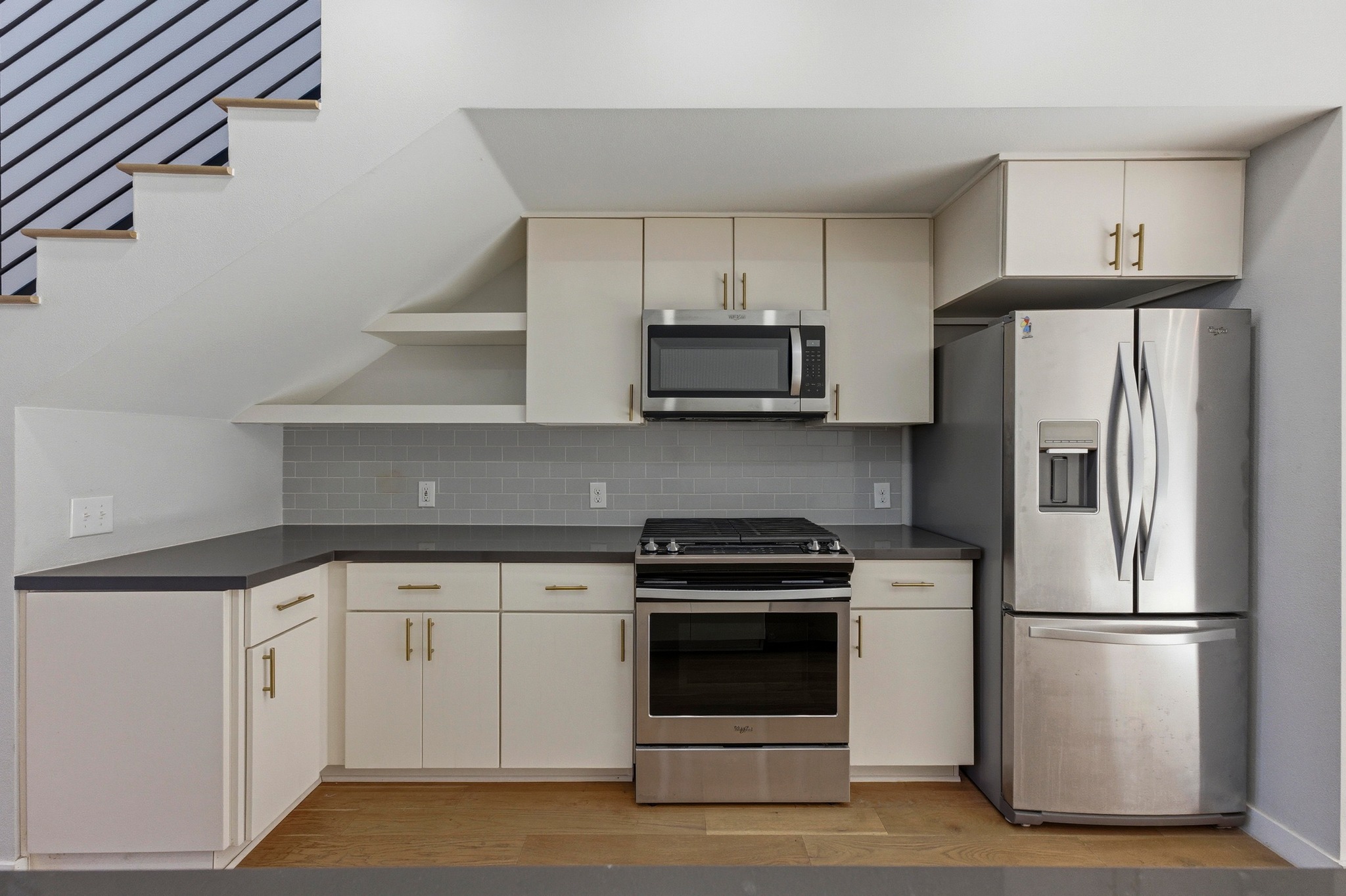 2002 East 7th Street, Unit 242 Austin, TX 78702 - Photo 7 of 34 Kitchen featuring open shelves, dark countertops, stainless steel appliances, light wood-type flooring, and backsplash