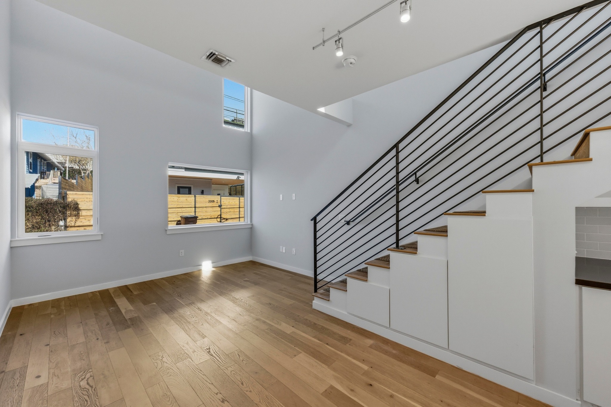 2002 East 7th Street, Unit 242 Austin, TX 78702 - Photo 8 of 34 Stairs with wood-type flooring, a high ceiling, and rail lighting