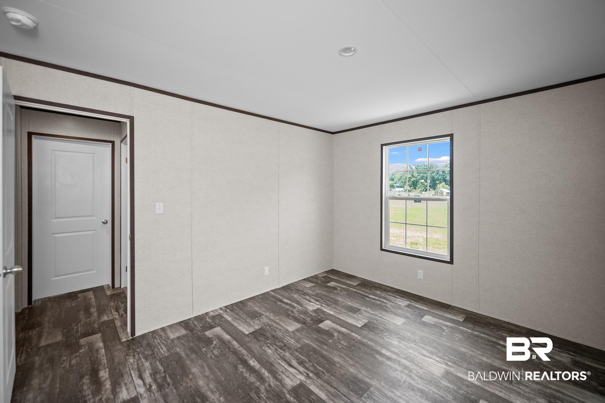 21601 Westside Loop Silverhill, AL 36576 - Photo 33 of 42 Spacious room featuring wood-finish flooring, light-toned walls, a window with exterior scenery, a white paneled door, and recessed lighting