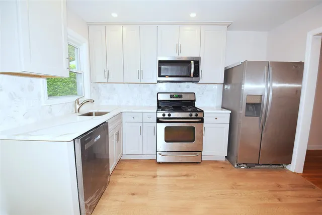 a kitchen with a sink white cabinets and stainless steel appliances