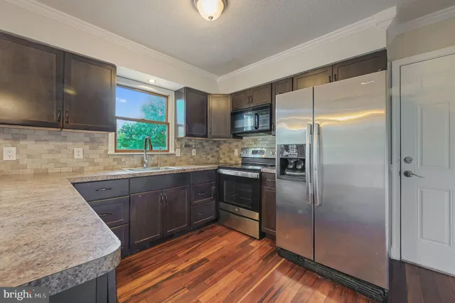 a kitchen with stainless steel appliances granite countertop a refrigerator a sink dishwasher a stove with wooden cabinets and floor