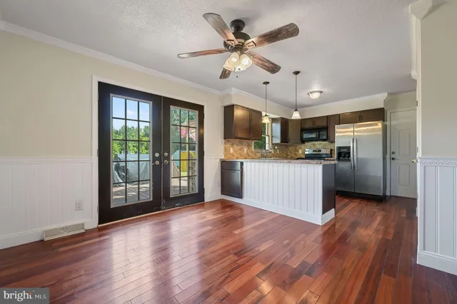 a open kitchen with stainless steel appliances granite countertop a refrigerator stove top oven and cabinets with wooden floor