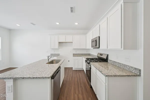 a kitchen with granite countertop white cabinets and stainless steel appliances