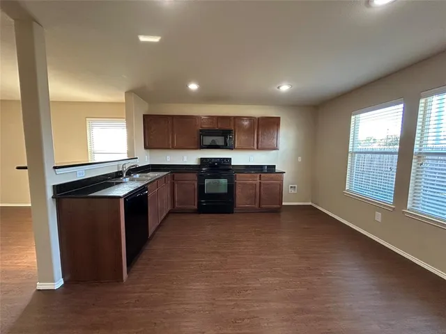 a large kitchen with stainless steel appliances granite countertop a stove top oven a sink and a microwave