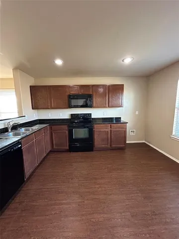 a large kitchen with stainless steel appliances granite countertop a stove a sink and a microwave