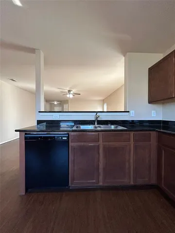 a large kitchen with a sink and dishwasher a stove top oven with wooden floor