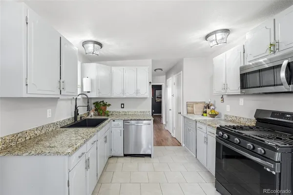 a kitchen with granite countertop a stove sink and cabinets
