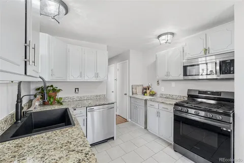 a kitchen with stainless steel appliances granite countertop a stove a sink dishwasher and a microwave oven with white cabinets