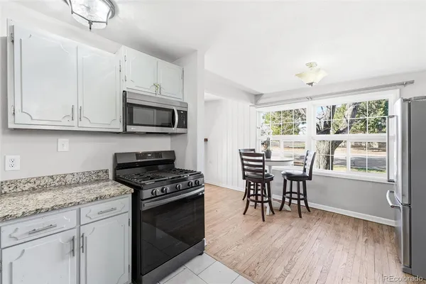 a kitchen with granite countertop wooden floors wooden cabinets dining table and stainless steel appliances