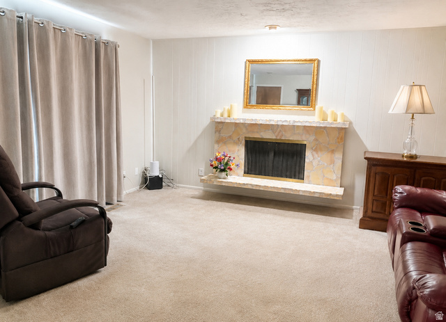 1020 Wilmar Place Centerville, UT 84014 - Photo 2 of 22 Living area featuring a stone-clad fireplace, paneled accent wall, and neutral carpet flooring