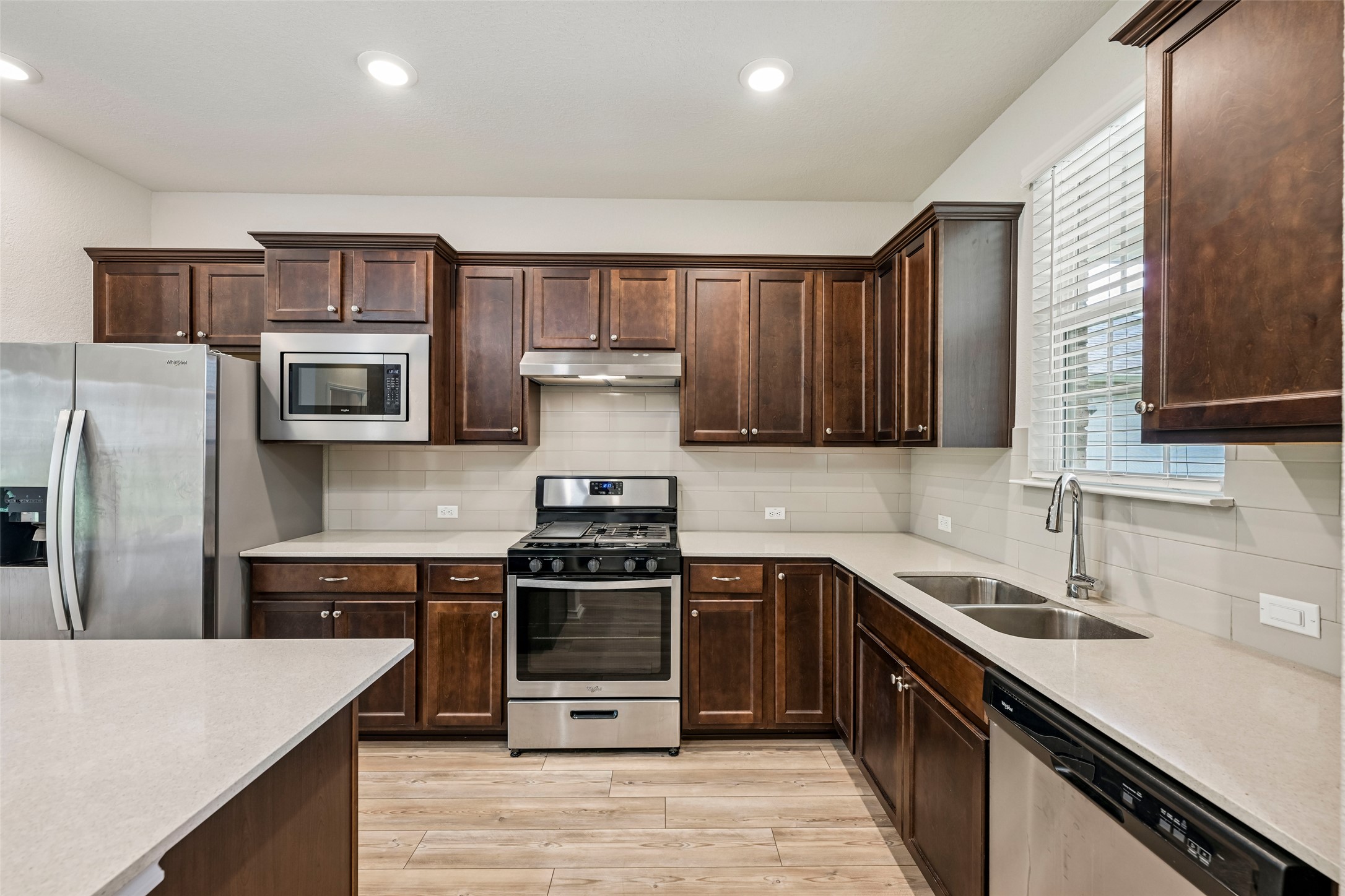 401 Yorktown Street Georgetown, TX 78633 - Photo 8 of 38 Kitchen featuring dark wood cabinetry, light-toned countertops, and stainless steel appliances including a gas range and built-in microwave