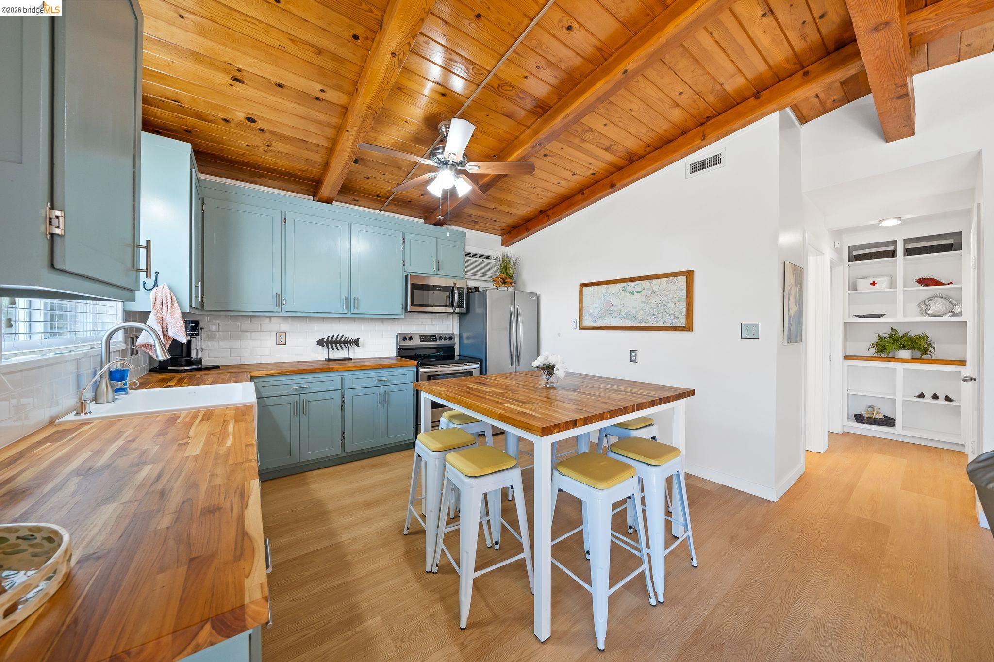 1704 Taylor Road Bethel Island, CA 94511 - Photo 27 of 73 Kitchen featuring wood-finish flooring, vaulted wood-paneled ceiling with exposed beams, light blue cabinetry, butcher block countertops, and white subway tile backsplash