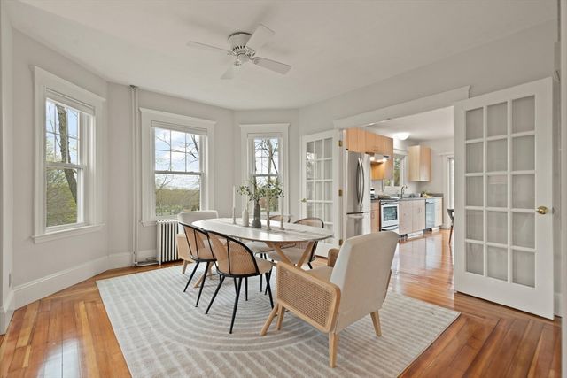 a dining room with wooden floor a chandelier a glass table and windows