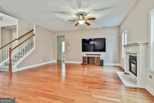 an empty room with wooden floor fan and windows