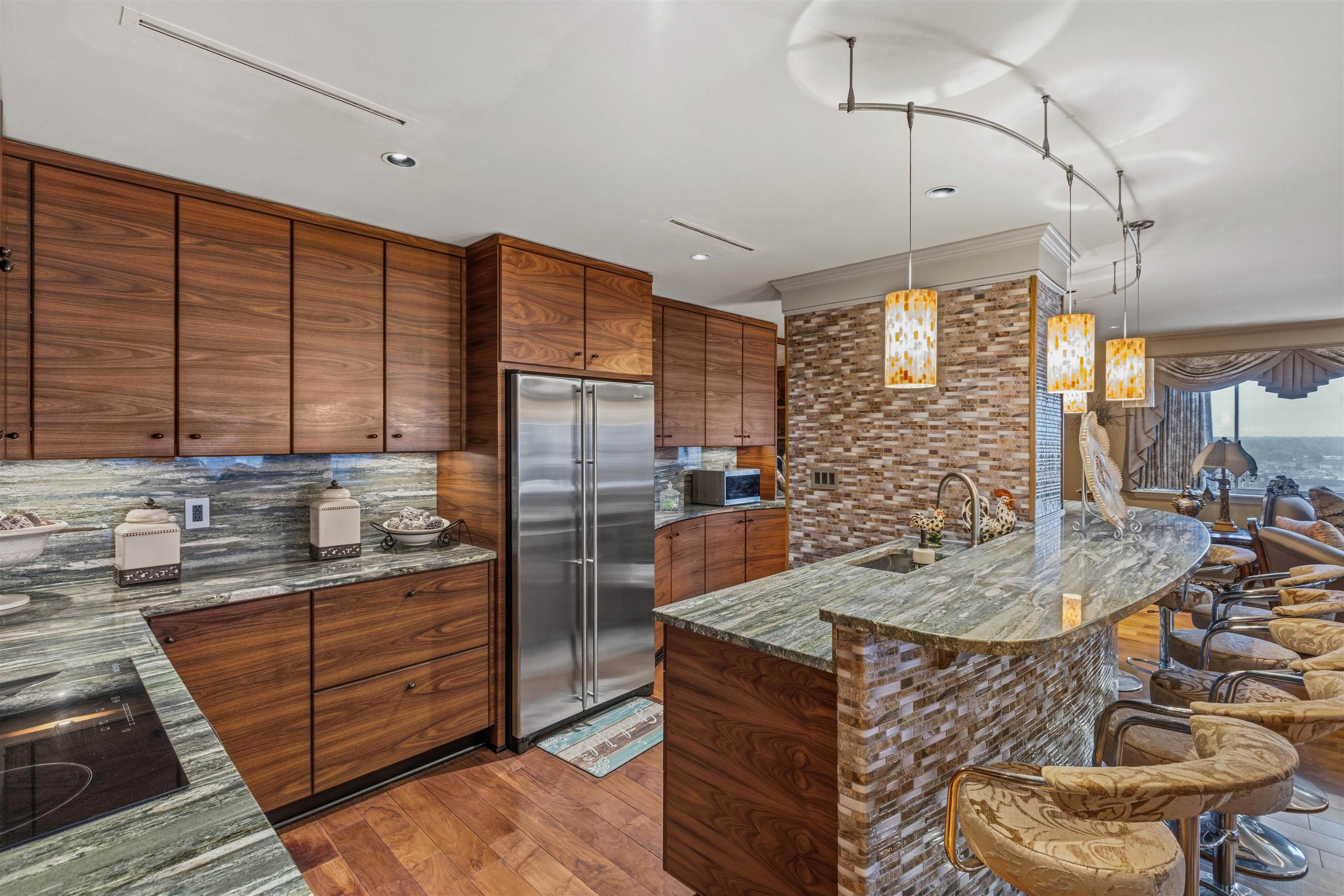 655 Riverside Drive, Unit 1208 Memphis, TN 38103 - Photo 16 of 29 Kitchen with a kitchen bar, stainless steel appliances, dark stone countertops, dark wood-type flooring, and hanging light fixtures