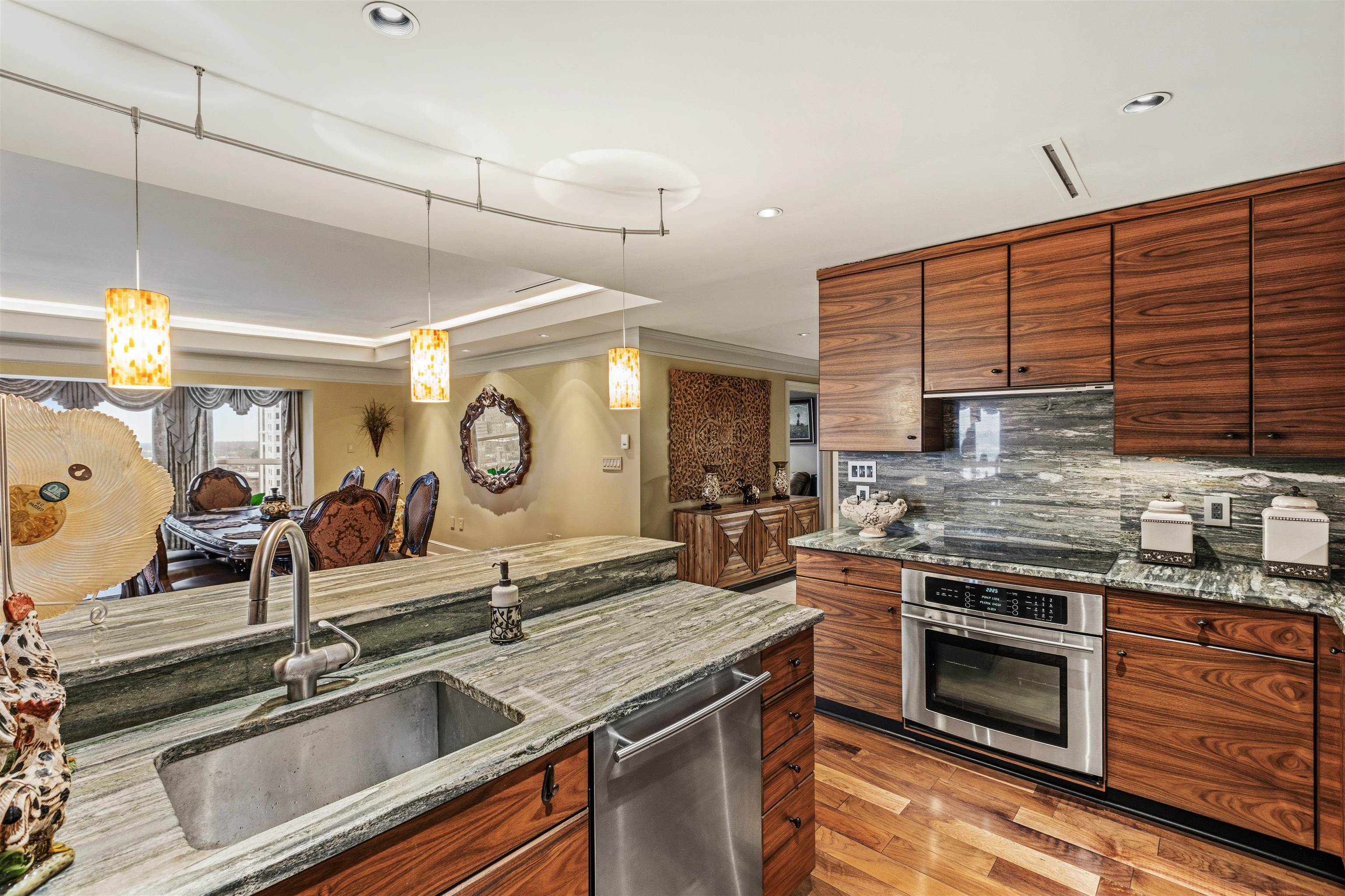 655 Riverside Drive, Unit 1208 Memphis, TN 38103 - Photo 17 of 29 Kitchen with light stone countertops, stainless steel appliances, hanging light fixtures, backsplash, and wood finish cabinets