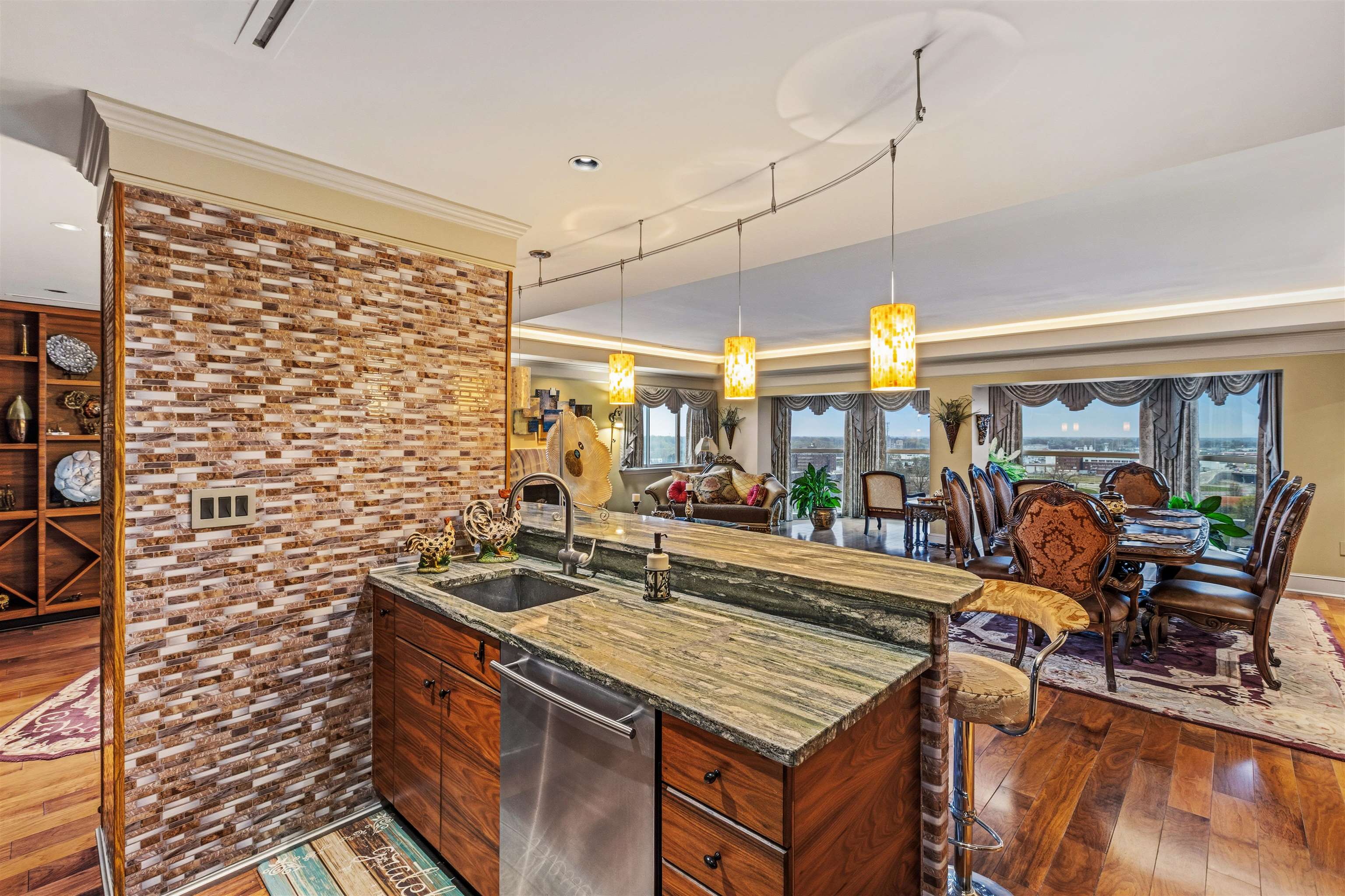 655 Riverside Drive, Unit 1208 Memphis, TN 38103 - Photo 18 of 29 Kitchen featuring a kitchen bar, dark wood-style flooring, hanging light fixtures, stainless steel dishwasher, and dark stone counters