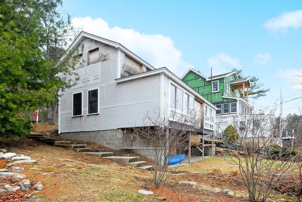 66 Pine Point Road Stow, MA 01775 - Photo 13 of 25 a view of a white house with large windows next to a road