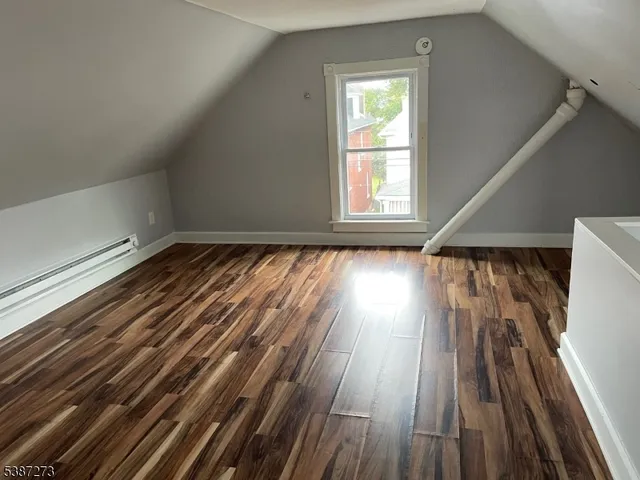 a view of an empty room and wooden floor and a window