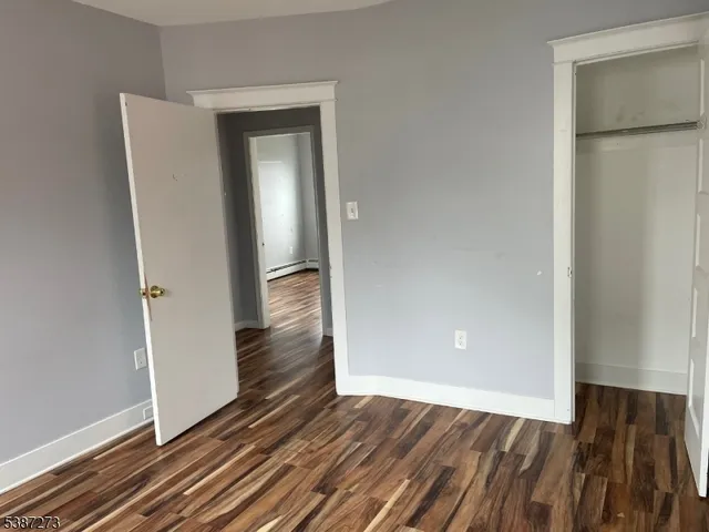 an empty room with wooden floor and a hallway