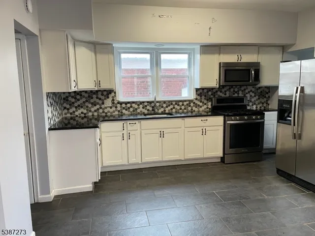 a kitchen with stainless steel appliances granite countertop a stove a microwave and a refrigerator