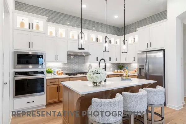 a kitchen with stainless steel appliances a stove a sink a refrigerator a center island a stove and white cabinets