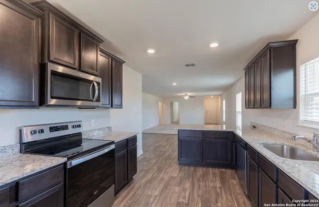 a kitchen with stainless steel appliances granite countertop wooden cabinets a stove top oven a sink and dishwasher