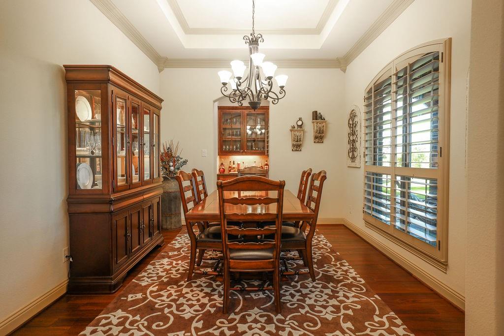 1387 Shadow Lakes Drive Wills Point, TX 75169 - Photo 5 of 30 Dining room with a chandelier, dark wood-style flooring, a tray ceiling, crown molding, and baseboards