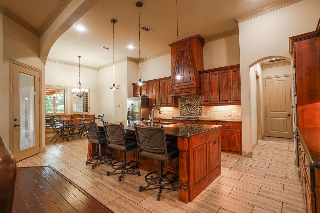 1387 Shadow Lakes Drive Wills Point, TX 75169 - Photo 8 of 30 Kitchen featuring crown molding, a sink, arched walkways, a kitchen breakfast bar, and stainless steel appliances
