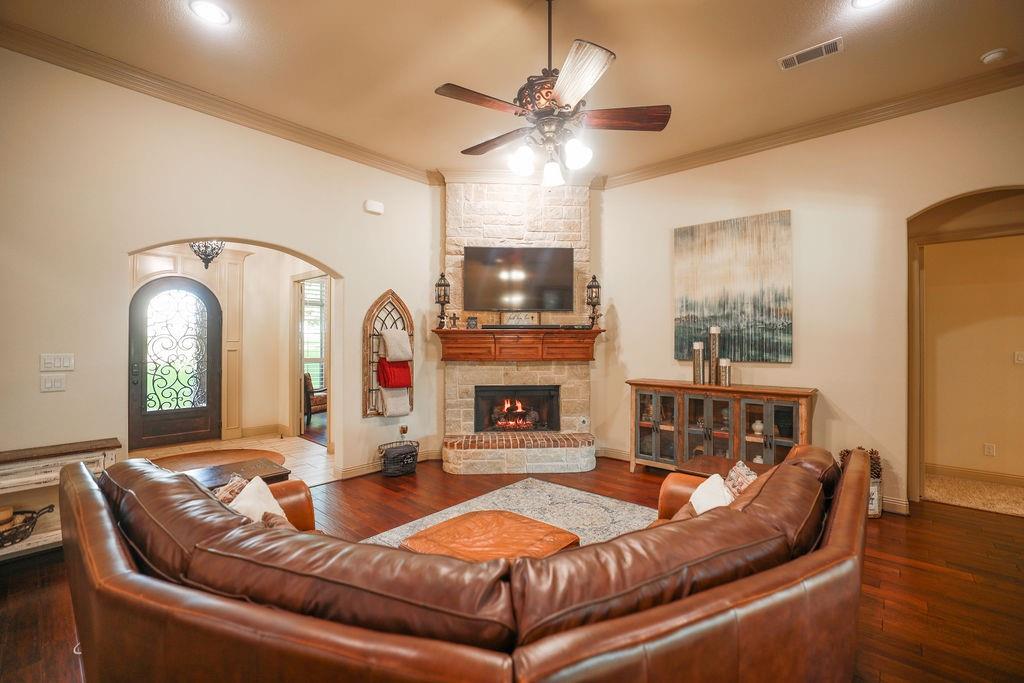 1387 Shadow Lakes Drive Wills Point, TX 75169 - Photo 9 of 30 Living room featuring arched walkways, hardwood / wood-style floors, ceiling fan, crown molding, and a fireplace