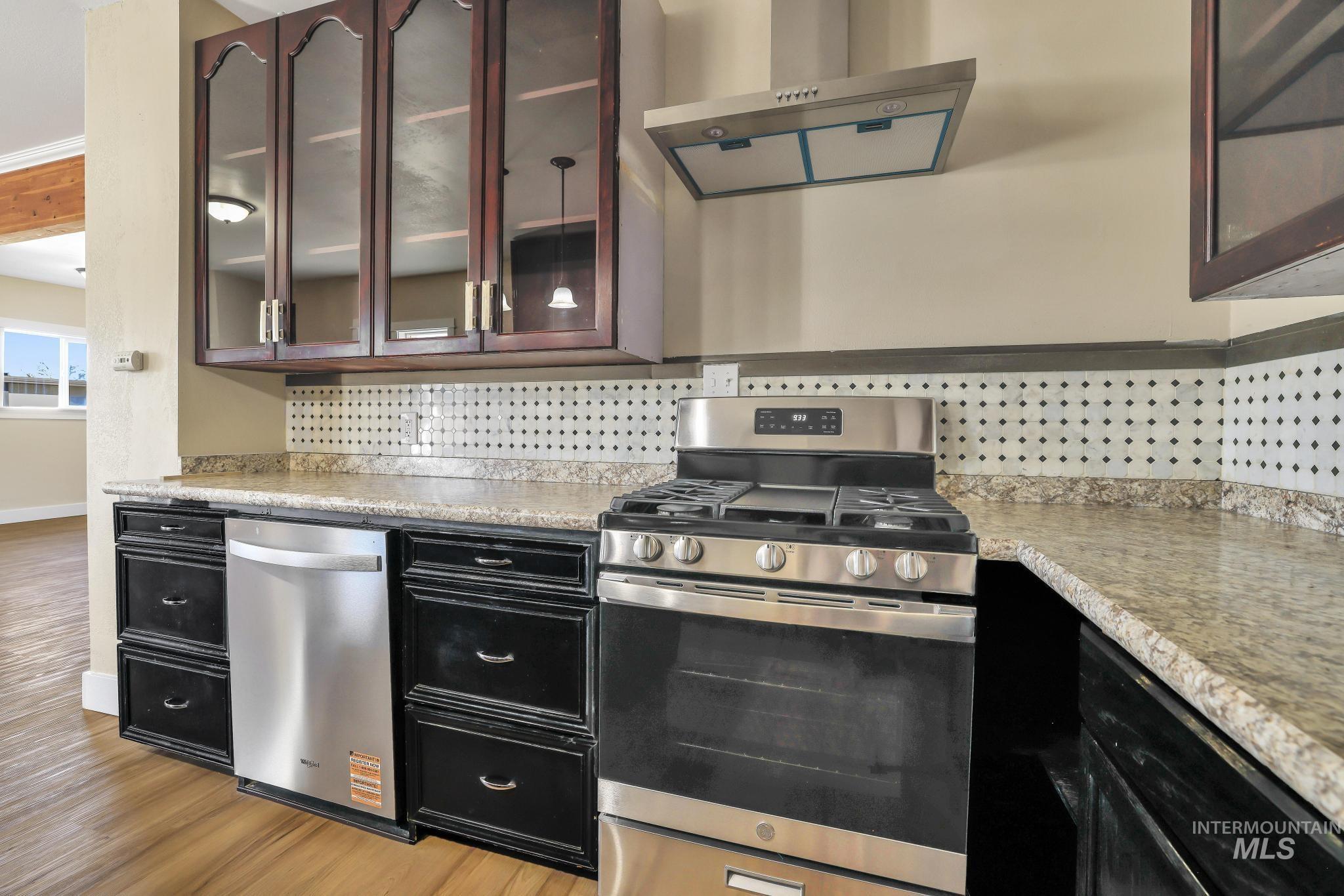 1226 Washington Street Gooding, ID 83330 - Photo 5 of 13 Kitchen with stainless steel appliances, extractor fan, glass fronted cabinets, and light countertops