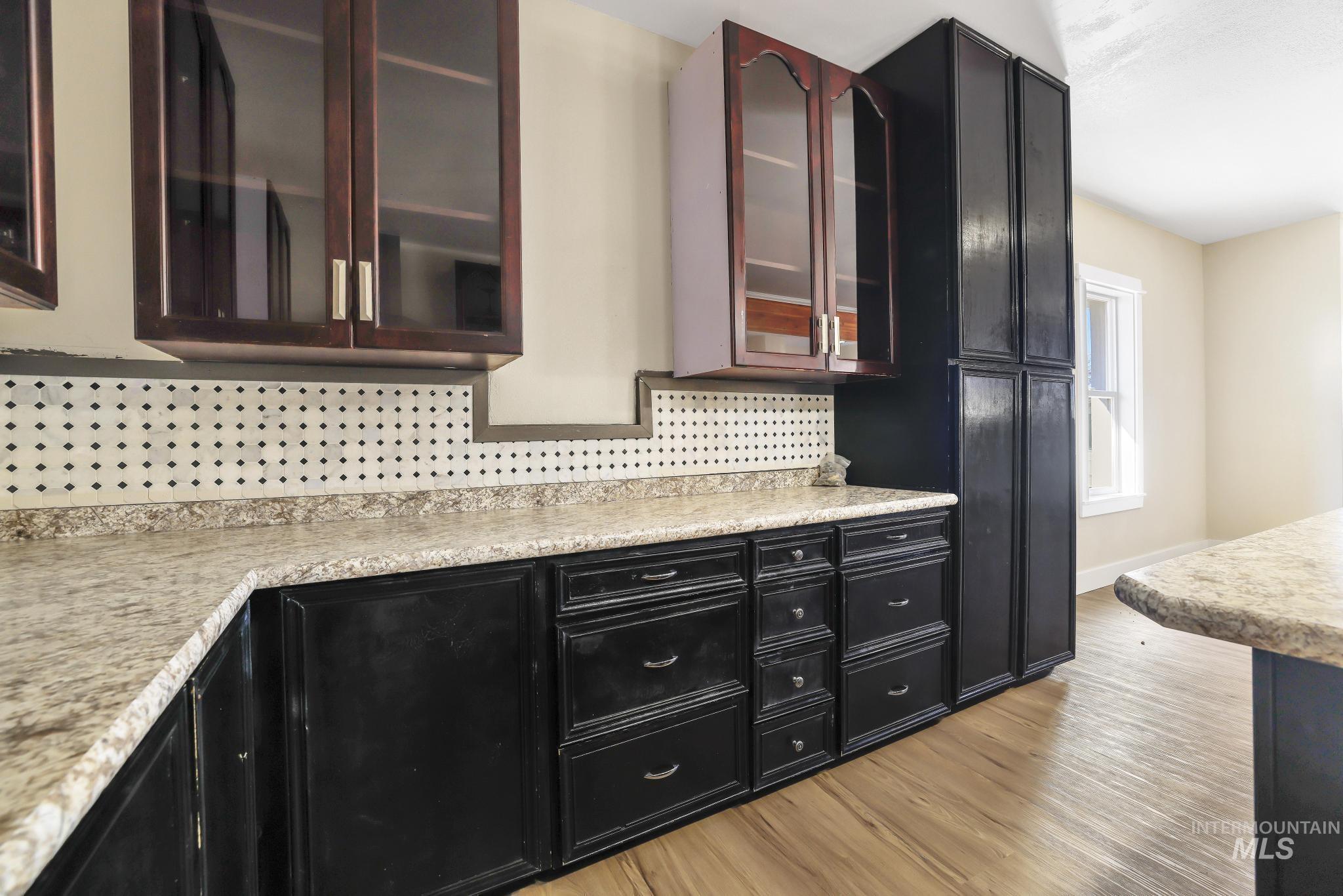 1226 Washington Street Gooding, ID 83330 - Photo 6 of 13 Kitchen with dark cabinetry, glass fronted cabinets, backsplash, and light countertops