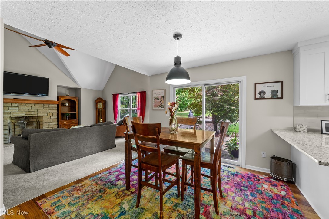 30825 Cannon Road Solon, OH 44139 - Photo 13 of 49 Dining area with wood finished floors, lofted ceiling, a textured ceiling, a fireplace, and a ceiling fan