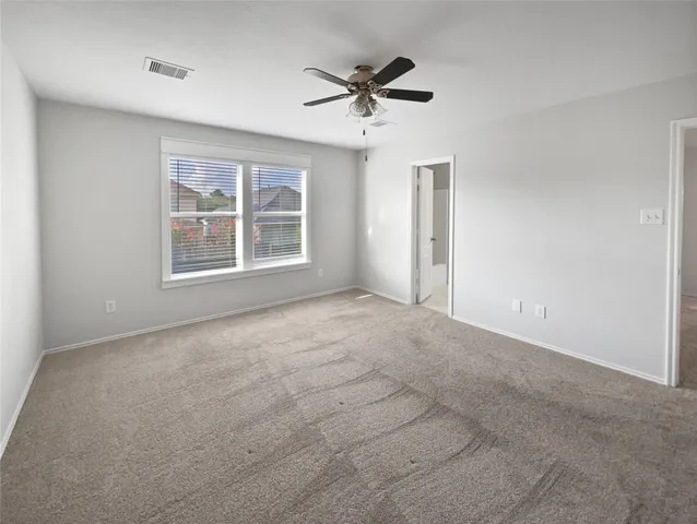 an empty room with a ceiling fan and windows