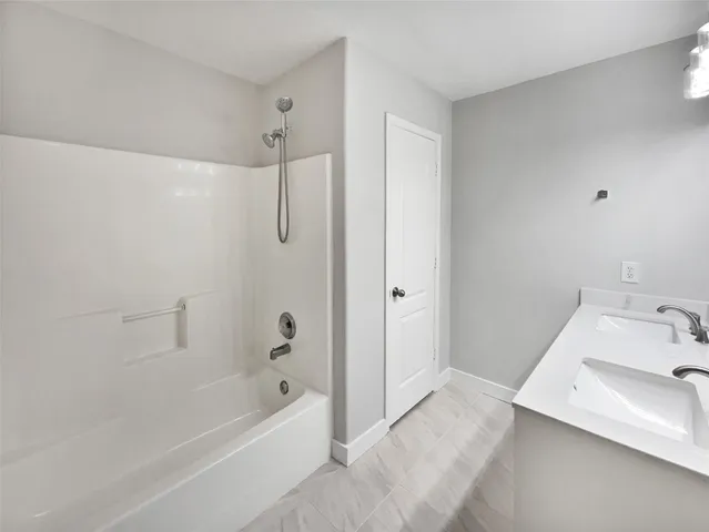 a bathroom with a tub sink vanity and shower